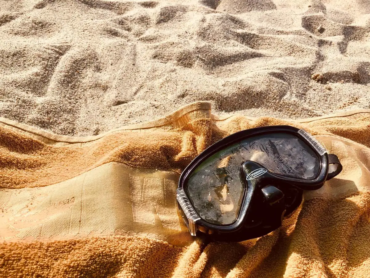 Scuba mask on towel on sandy beach