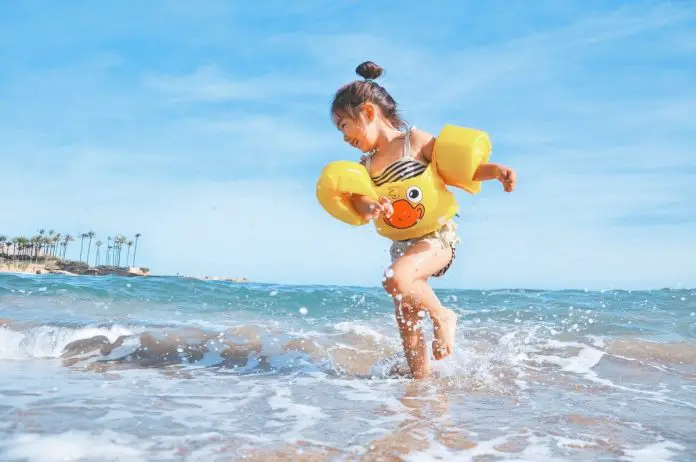 Little girl wearing floaties playing in the surf