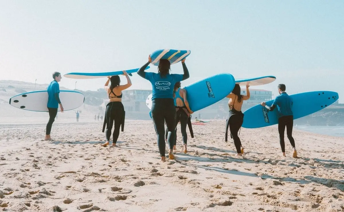 Group of people carrying surfboards over their heads on the beach