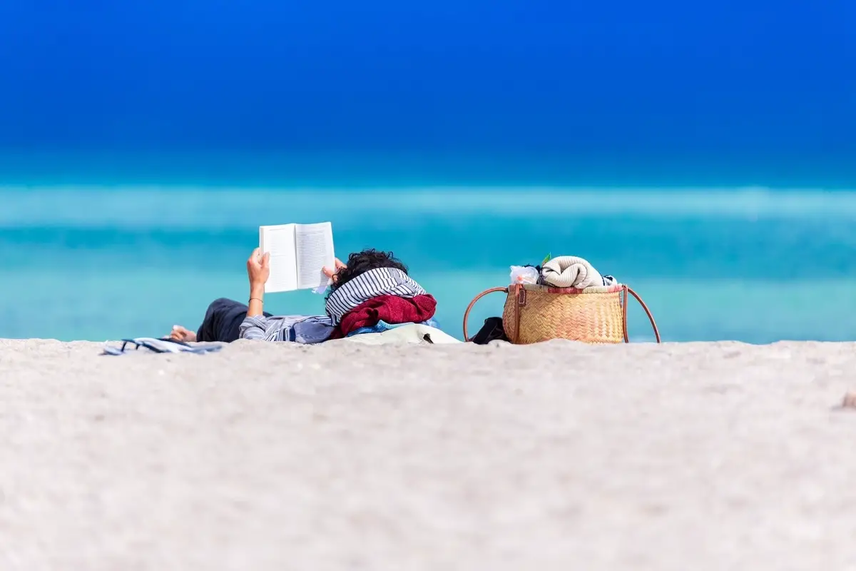 Man relaxing on the beach reading a book