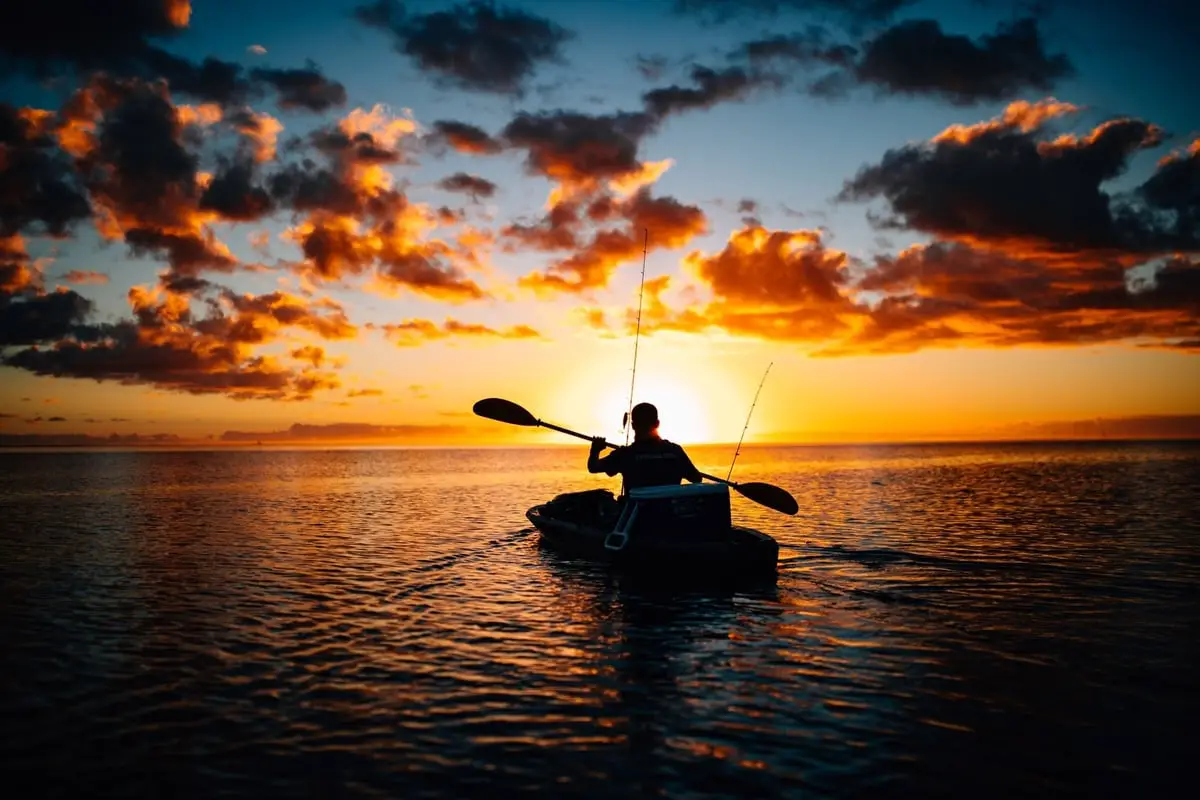 Photo of man canoeing on lake at sunset