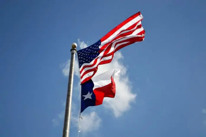 United States flag and Texas flag flying over a blue sky